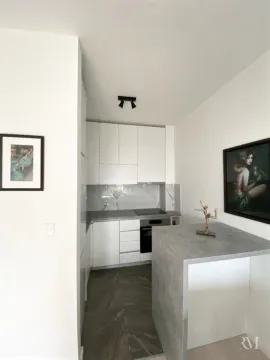 Moderna bijela kuhinja sa šankom i sivim radnim površinama. - image 7