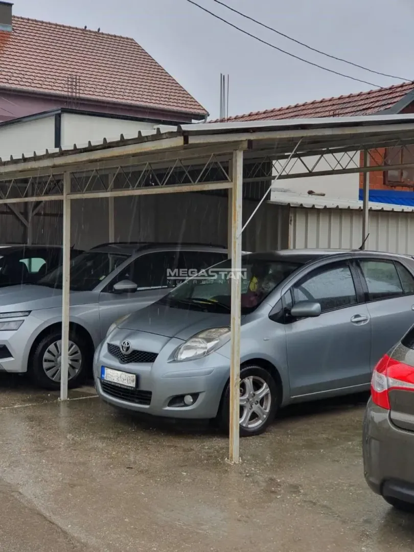 Natkriveni parking prostor sa parkiranim automobilima.