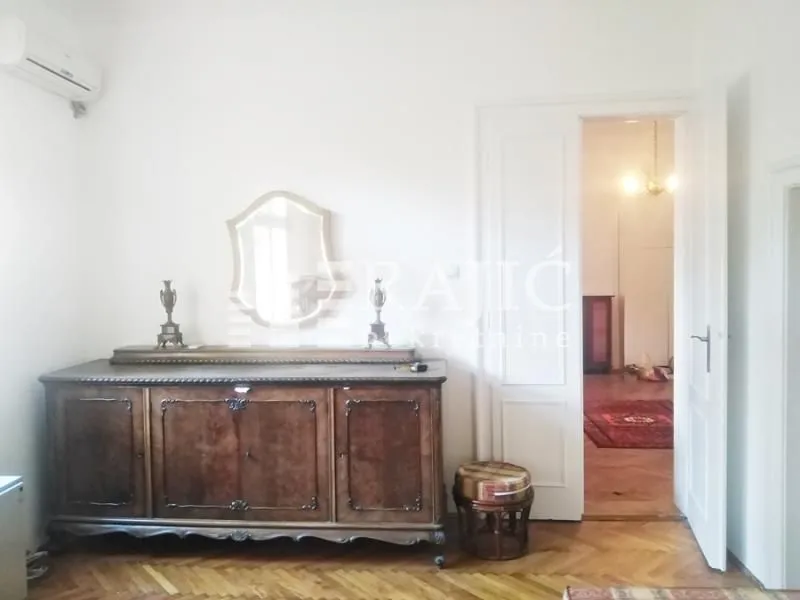 Living room with a wooden sideboard, mirror, and an open door leading to another room.