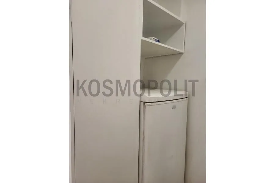 Deo kuhinje sa belim elementima i frižiderom.