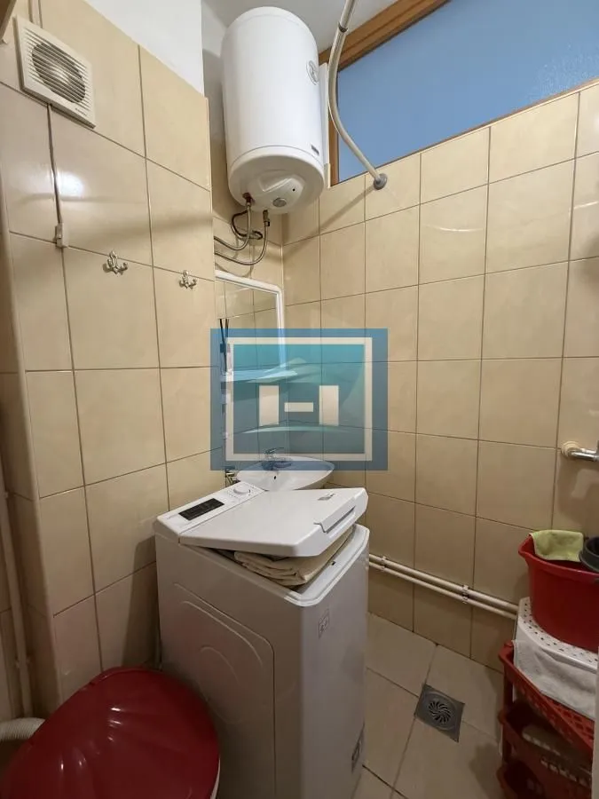 Tiled bathroom with a washing machine, water heater, and washbasin.