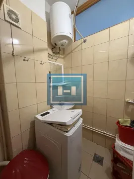 Tiled bathroom with a washing machine, water heater, and washbasin. - image 2