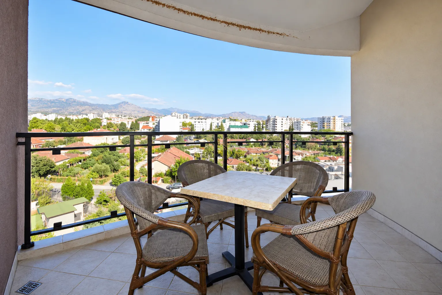 Covered terrace with a table, chairs, and an open view of the city.