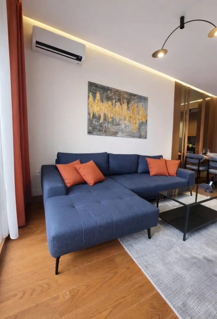 Living room with a blue sectional sofa, coffee table, and air conditioning.