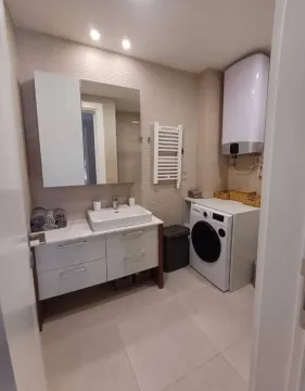 Modernly equipped bathroom with a washbasin, mirror, and washing machine. - image 8