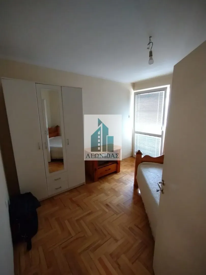 Smaller bedroom with a bed, wardrobe, and parquet flooring.