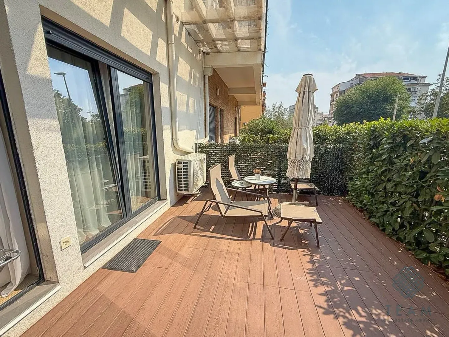 Spacious wooden terrace with outdoor seating and a sun umbrella.