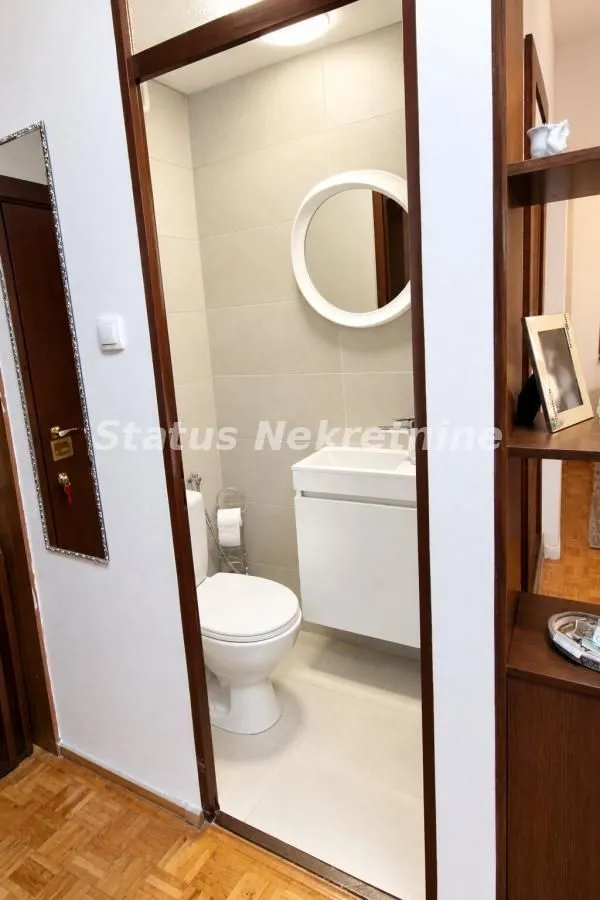 Pogled iz hodnika na uređeno kupatilo sa sanitarijama.