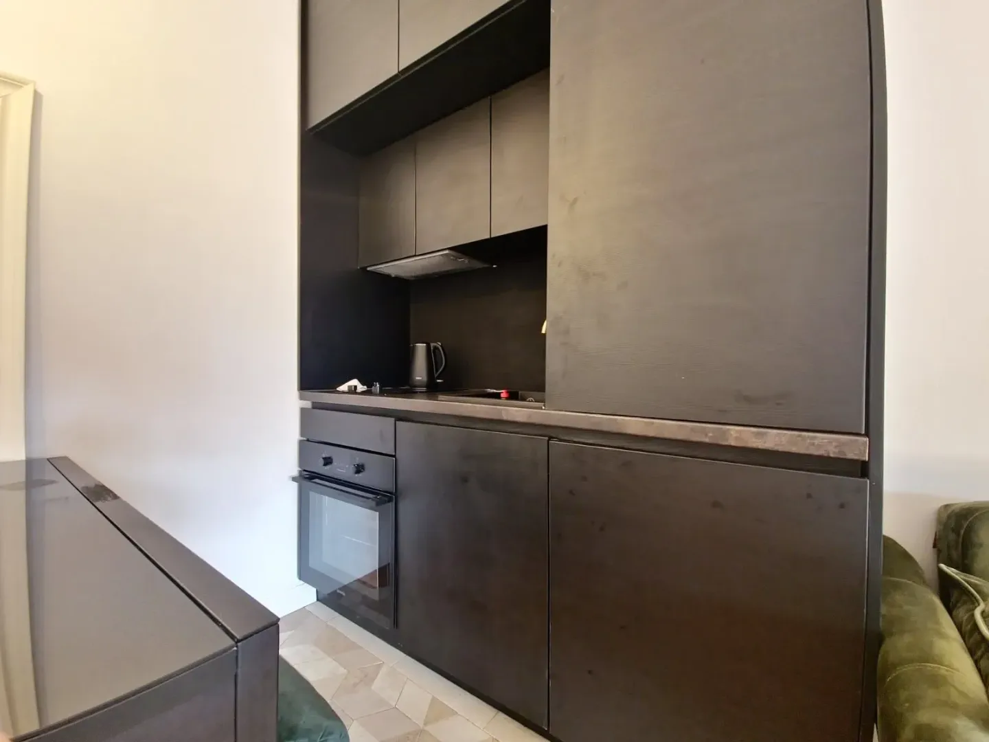 Modern black kitchen with built-in oven and cabinetry.