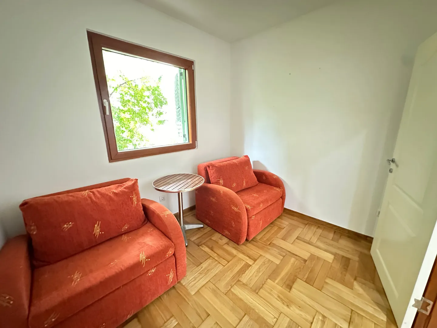 Living room with two orange armchairs, a small table, and a window.