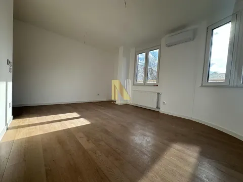 Prazna soba sa drvenim podom, belim zidovima i prozorima. - image 3