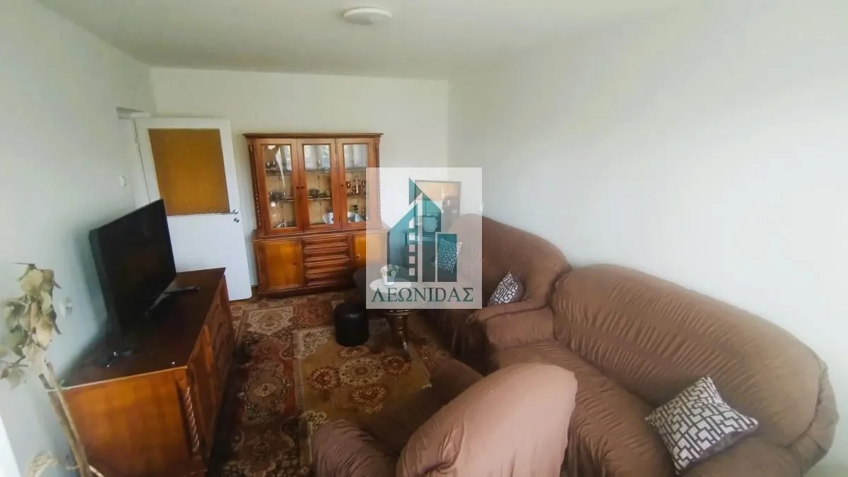 Living room with sofa set, wooden furniture, and a carpet.