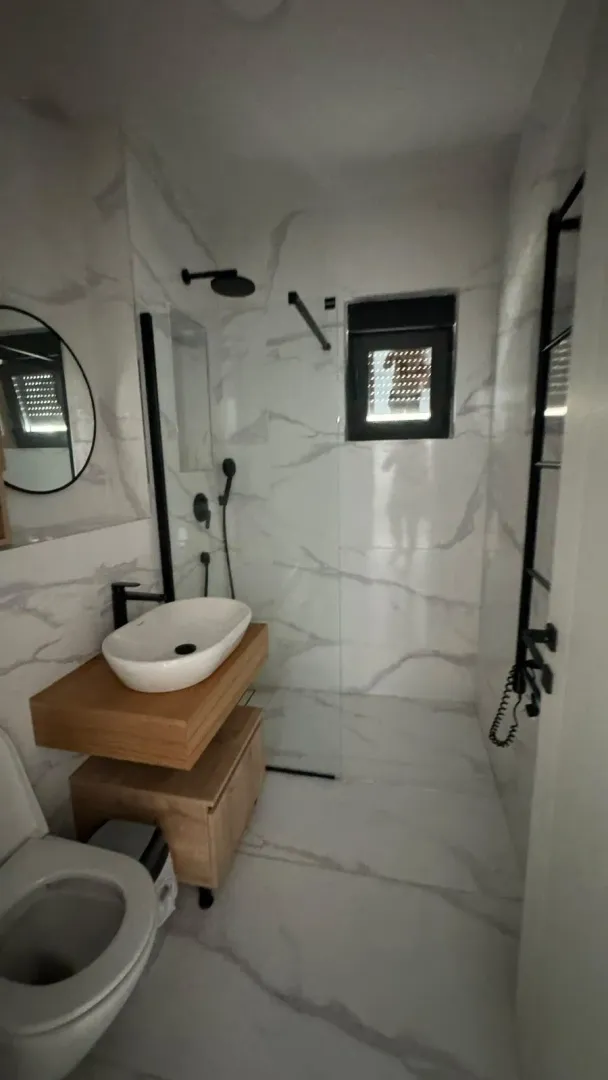 Moderne kupatilo sa tuš kabinom, umivaonikom i wc šoljom.