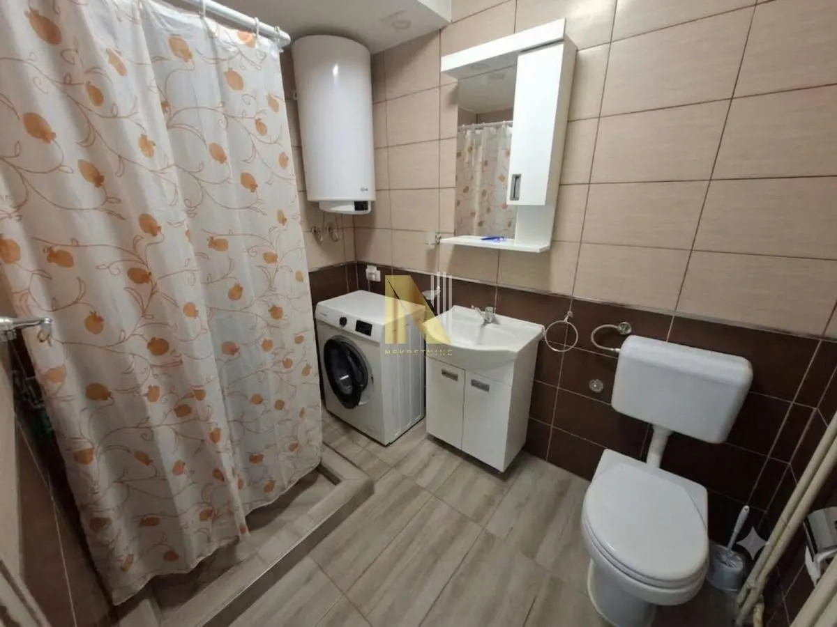 Compact bathroom with a shower enclosure, washbasin, washing machine, and toilet.