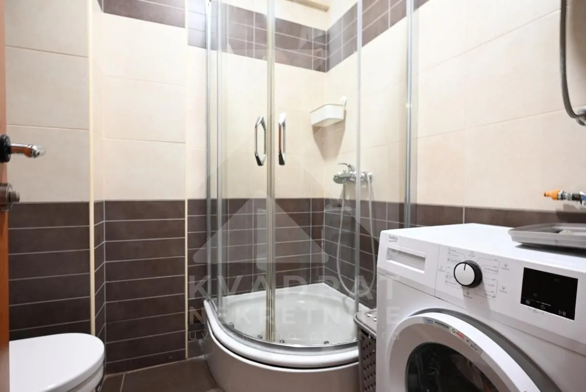 Kupatilo sa tuš kabinom, WC šoljom i veš mašinom.