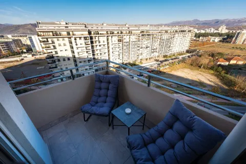 Small furnished balcony with two armchairs and a small table, overlooking buildings and surroundings. - image 16
