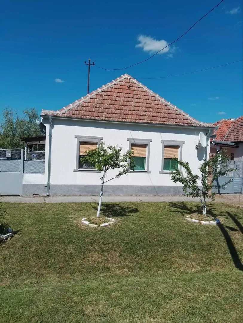 Prednji deo porodične kuće sa uređenim travnjakom i dvorištem.