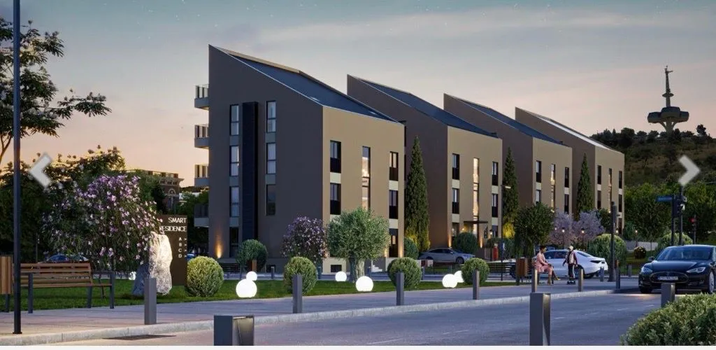 Spoljašnji izgled modernih stambenih zgrada sa uređenim dvorištem.