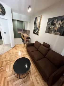 Dnevna soba sa braon trosjedom, stočićem i pogledom na kuhinju u pozadini. - image 8