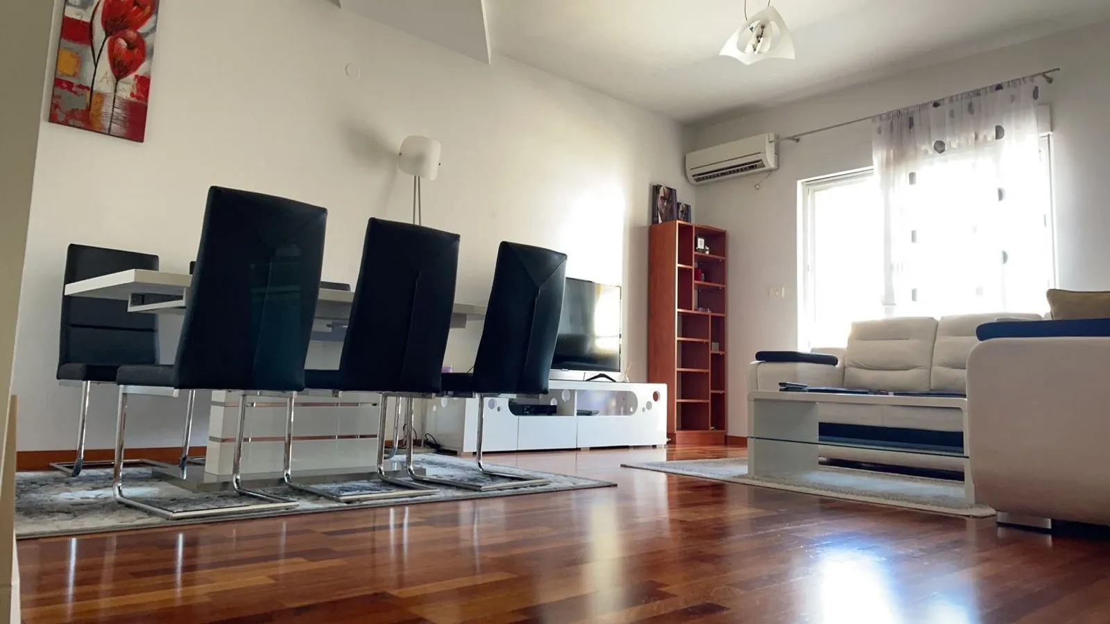 Svijetla dnevna soba sa trpezarijskim stolom i kožnom garniturom.