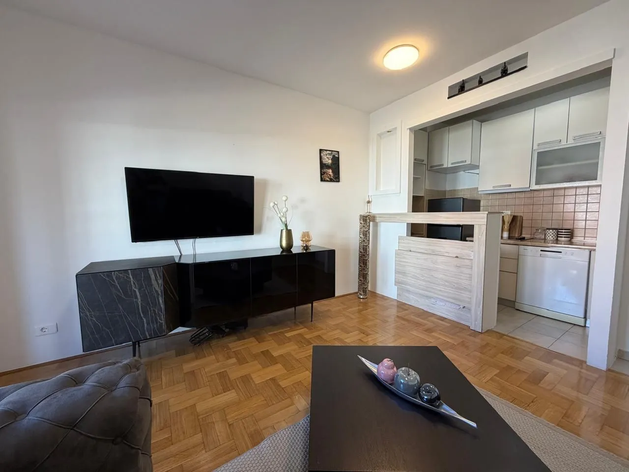 Living room with TV cabinet and a view of the kitchen.