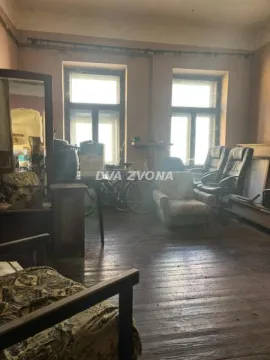Stariji dnevni boravak sa drvenim podom, starim nameštajem i dva prozora. - image 2
