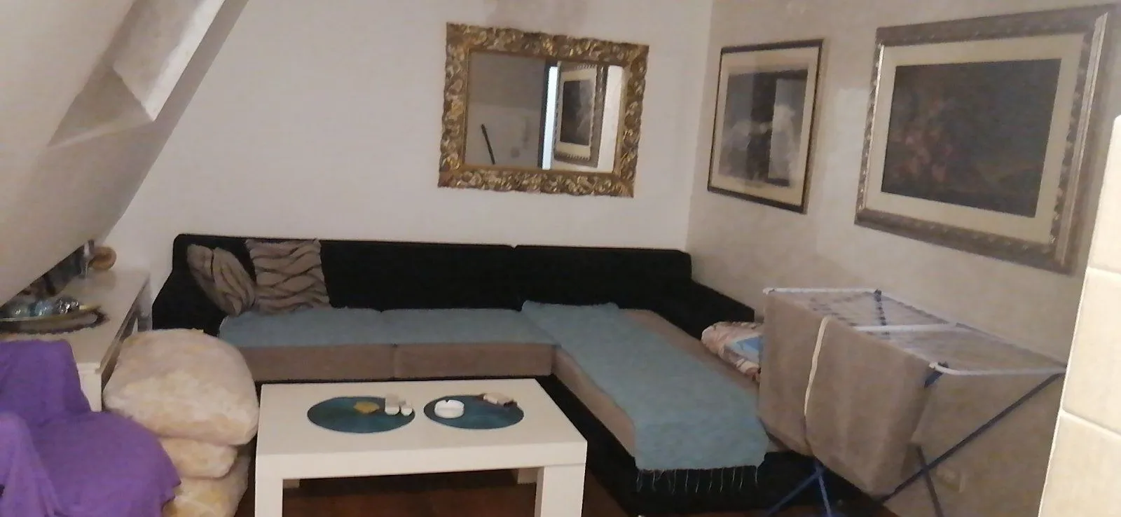 A living room featuring a large corner sofa, a white coffee table, and a wall mirror.
