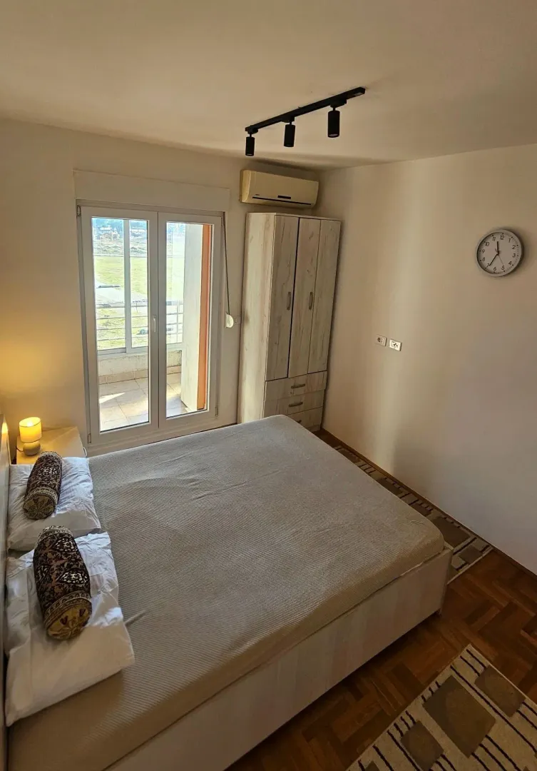 Namještena spavaća soba sa bračnim krevetom, garderoberom i izlazom na terasu.