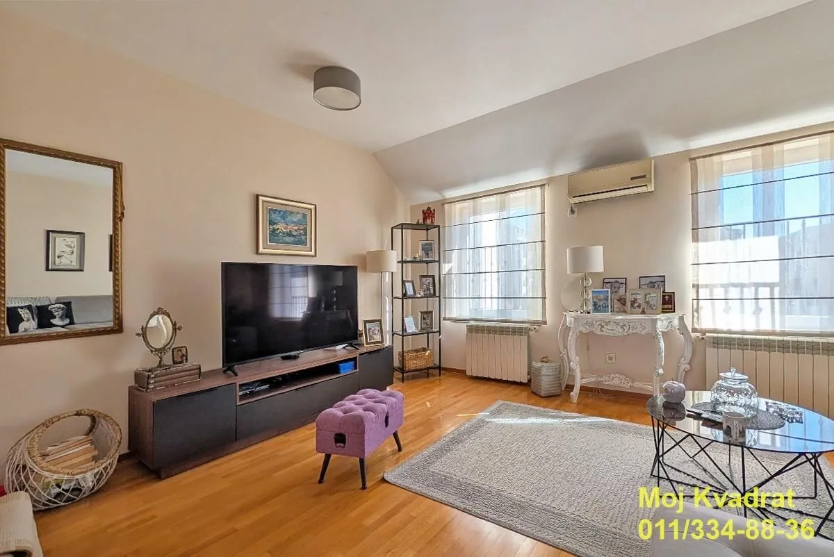 Living room with furniture, television, and wooden flooring.