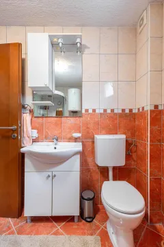 Bathroom equipped with a vanity unit with sink, mirror, and toilet. - image 20