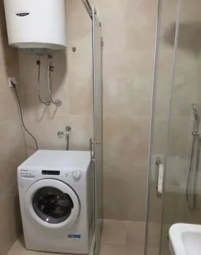 Smaller bathroom with a shower cabin, water heater, and washing machine. - image 11