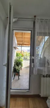 View through the open door onto a covered terrace with flowers and greenery. - image 14