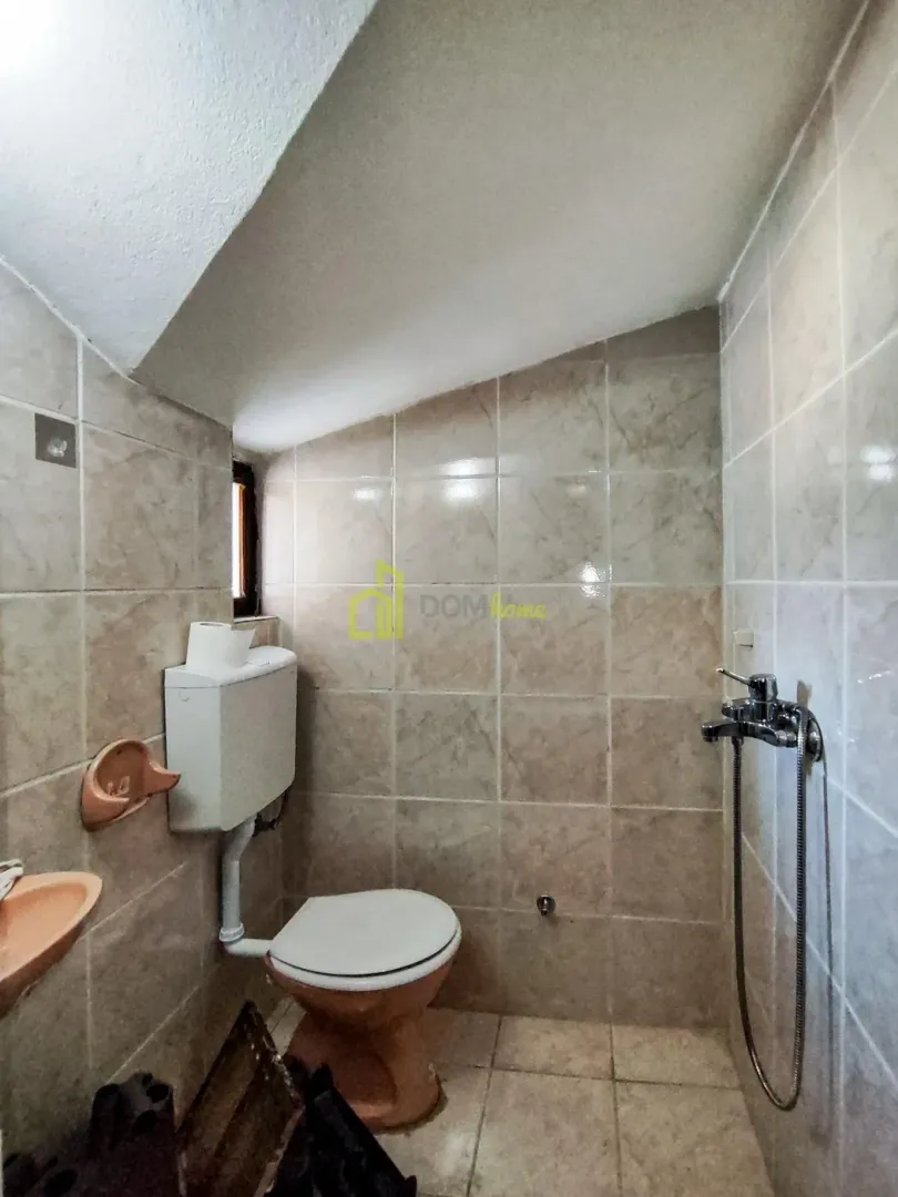 Small bathroom with a shower, toilet, and tiled walls.