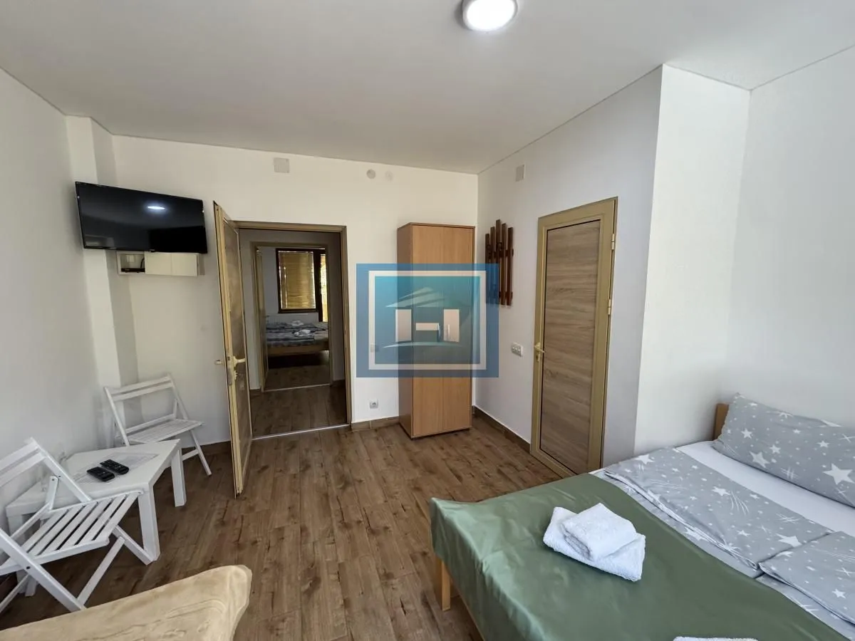 Furnished bedroom with a bed, wardrobe, and wall-mounted TV.