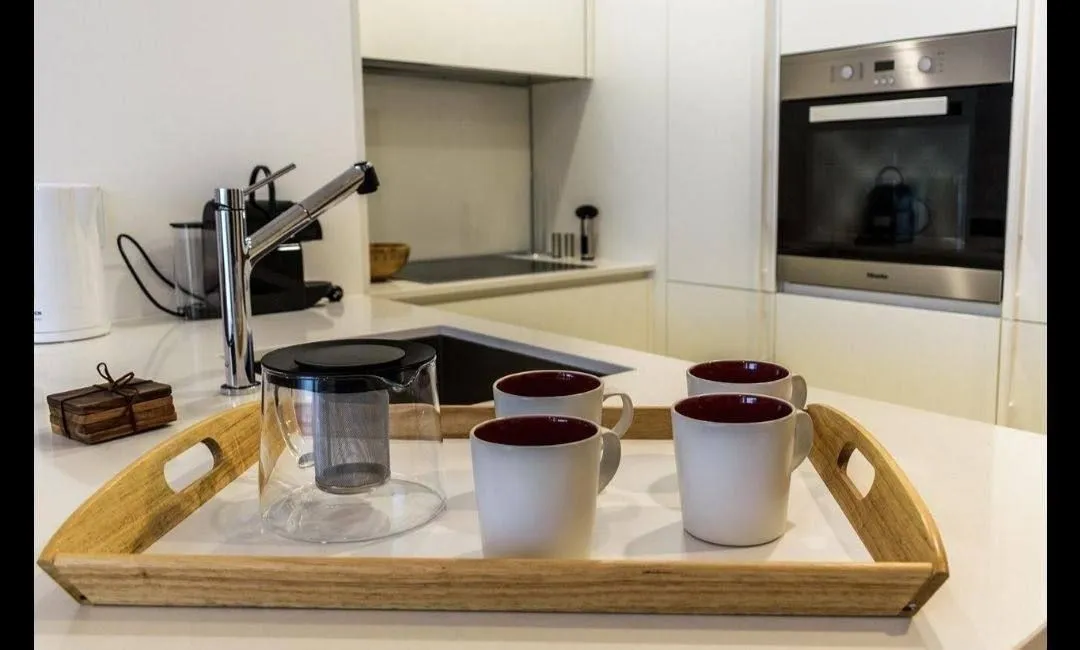 Modern kitchen with white cabinetry and a wooden tray on the countertop.