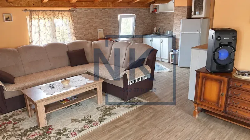 Living room with a sectional sofa, coffee table, and a kitchen area in the background.