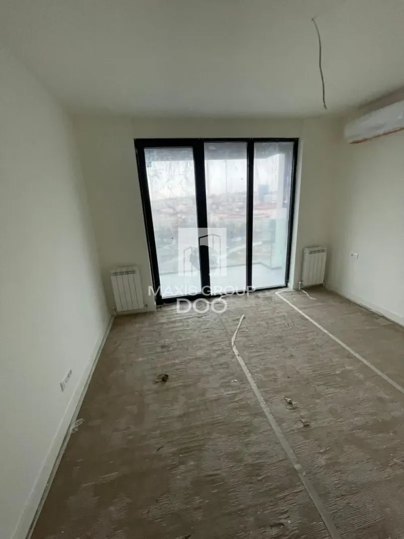 Empty unfinished room with balcony doors and a radiator.