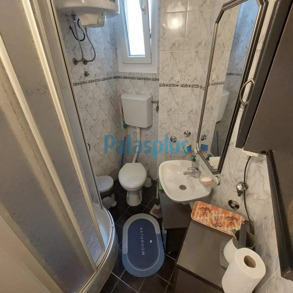 Smaller bathroom with a shower cabin, washbasin, and toilet.