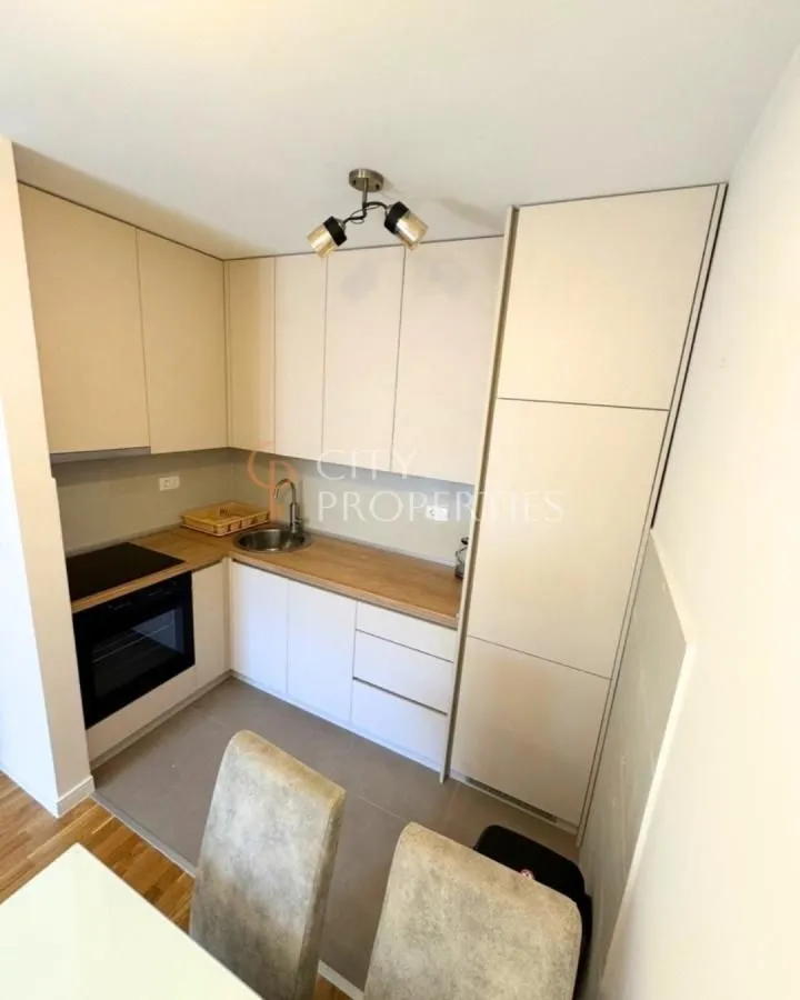 Compact kitchen with white cabinetry and a built-in oven.