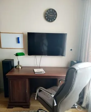 Study room with a desk, chair, and a wall-mounted TV. - image 10