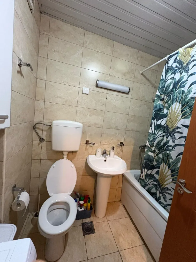 Manje kupatilo sa umivaonikom, WC šoljom i kadom sa zavjesom.