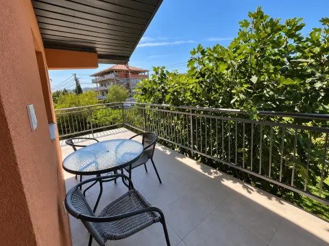 Covered balcony with seating furniture and a view of greenery. - image 5
