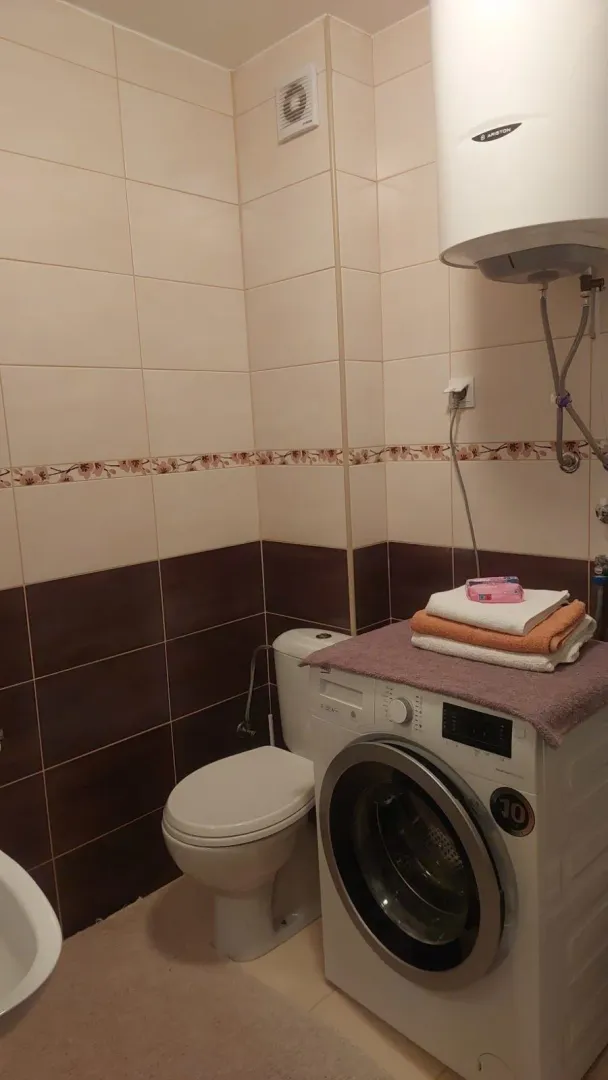 Bathroom with a toilet, washing machine, and water heater.