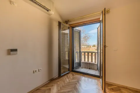 An empty room with parquet flooring and an open balcony door. - image 10
