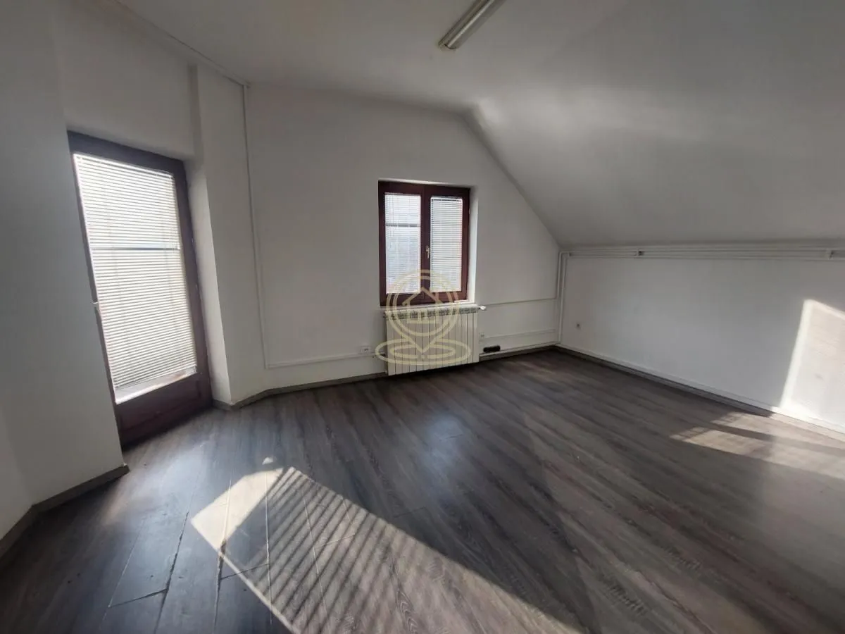 Empty room with wooden flooring, white walls, a window, and a balcony door.