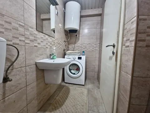 Tiled bathroom equipped with a washbasin, washing machine, and water heater. - image 22