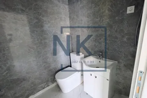 Small bathroom with a washbasin, toilet, and grey marble tiles. - image 16