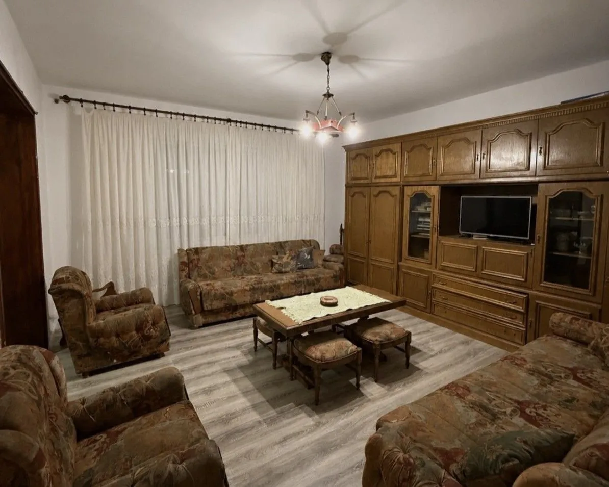 Spacious living room with seating set and a large wooden wardrobe.