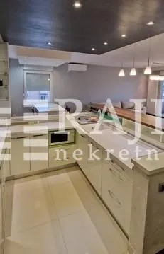 Moderna i uredna kuhinja sa otvorenim pogledom na dnevni boravak.