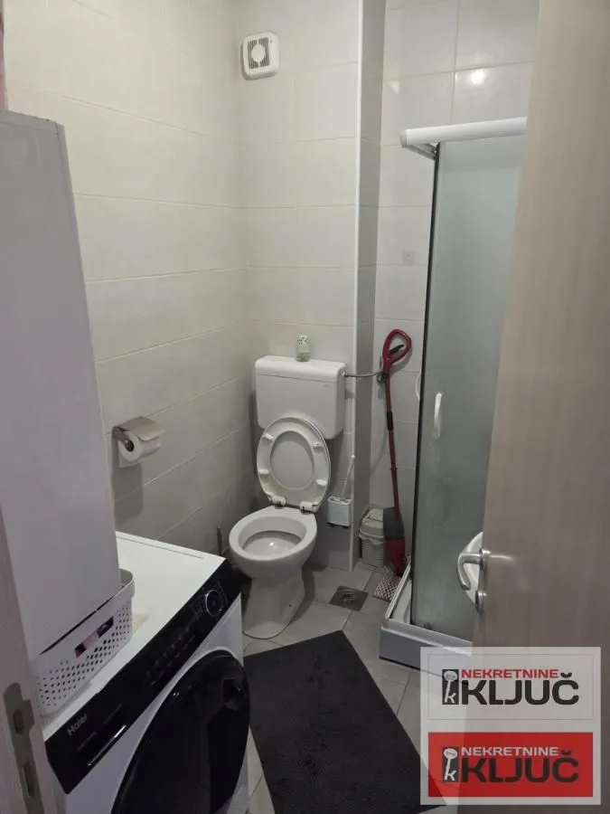 Kupatilo sa toaletom, tuš kabinom i veš mašinom.